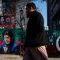 People walk past a banner with a picture of the former Prime Minister Imran Khan outside the party office of Pakistan Tehreek-e-Insaf (PTI), a day after the general election, in Lahore