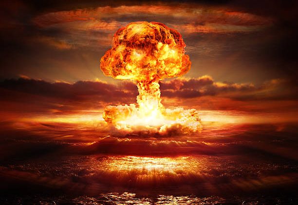 testing of atomic bomb over ocean with mushroom clouds – red destroy
