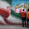 Iranian men put campaign posters on a wall during the last day of election campaigning in Tehran